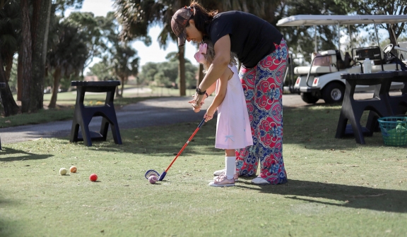 Woman teaching child to play golf